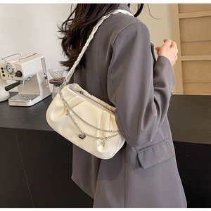 Détail d'un sac à bandoulière plissé blanc crème avec chaîne coeur argentée et sangle