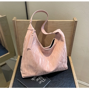 Detail view of pink tote bag with pleated leather texture on a wooden chair