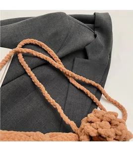 Detail of soft brown knitted shoulder strap and woven texture on a small crossbody bag