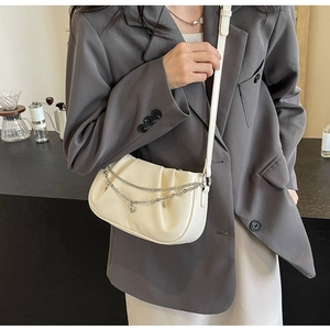 Détail du sac bandoulière en cuir plissé crème avec chaînes argentées et pendentif cœur