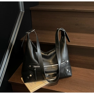 Gros plan détaillé du sac cabas en cuir noir mat avec rivets et logo métallique