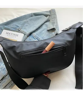 Detail of the front zipper pocket on a black nylon moon bag holding a lipstick