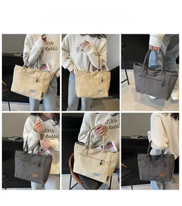 Detail view of canvas tote bag showing front zipper pocket and side compartments in two colors