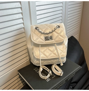 Detailed close-up of white quilted leather backpack with silver turn-lock and chain strap