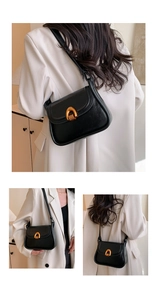 Detail of minimalist black saddle bag with lychee texture and gold metal buckle clasp