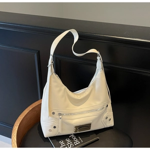 Détails des rivets argentés et de la fermeture éclair sur le sac hobo en cuir crème
