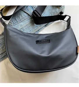 Detail of black nylon crescent bag with adjustable strap and branding plate