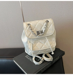 Detail of white quilted leather backpack with silver metal chain and twist-lock closure