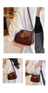 Detail of retro brown saddle bag featuring a gold horseshoe buckle and matte faux leather