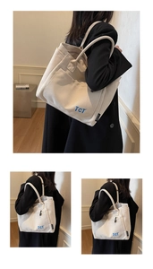 Detailed close-up of large canvas tote bag with blue TCT text and durable long handles