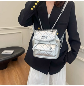 Close-up of silver quilted backpack featuring metallic chain strap and twist-lock detail