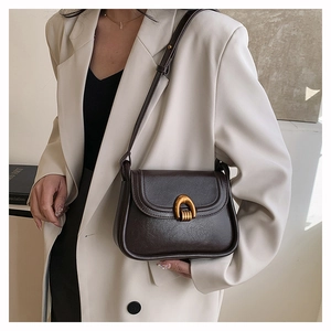 Close-up of a dark brown saddle bag with premium leather texture and gold hardware