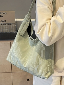 Minimalist light green tote bag with wrinkled leather texture worn by a model in a soft setting