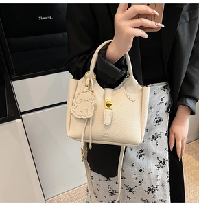 Détail du sac à main en cuir beige avec fermoir doré et pendentif chiot