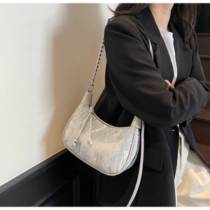 Détail du sac hobo argenté avec texture plissée et élégante bandoulière en chaîne métal