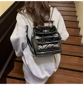 Close-up of black quilted chain backpack with silver metal twist lock on a casual model