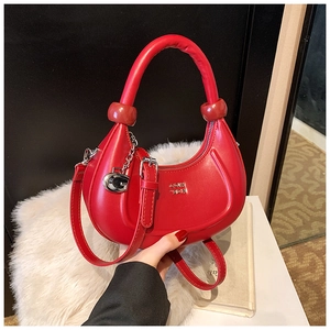 Dettaglio della borsa a mezzaluna in pelle rossa con pendente a G e zip in metallo