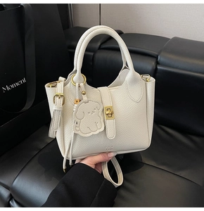 Détail d'un sac seau blanc en cuir grainé avec fermoir métallique et breloque chien chic
