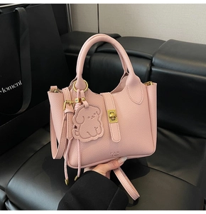 Détails du cuir grainé rose avec fermoir doré rotatif et charm de sac en forme de chien
