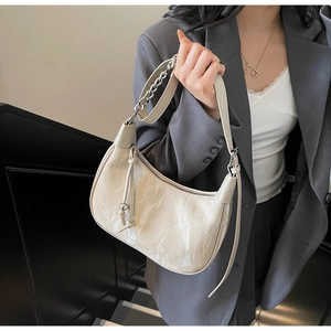 Détail d'un sac hobo blanc crème avec texture plissée brillante et chaîne argentée
