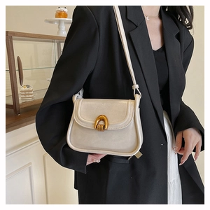Close-up of cream saddle bag featuring a polished gold U-shaped buckle and matte leather
