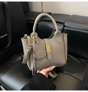 Détail du sac seau taupe en cuir grainé avec finitions dorées et breloque chien
