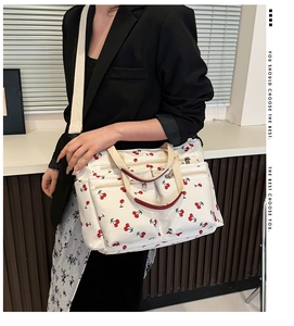 Detail view of canvas tote bag with cherry print featuring multiple zipper pockets