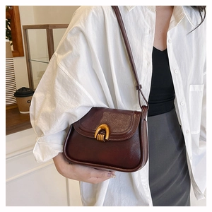 Detail view of a vintage dark brown saddle bag with premium leather and gold metal buckle