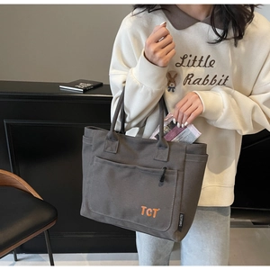 Detail of grey canvas tote bag with orange TCT embroidery and reinforced handles