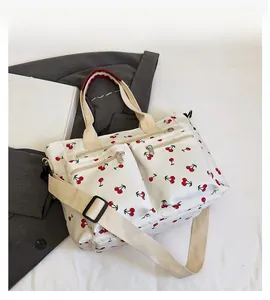 Detailed view of the red cherry print on white tote bag with functional zipper pockets