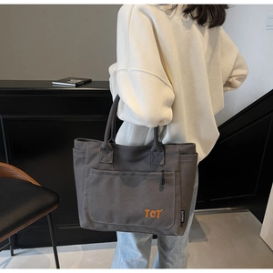 Detail of grey canvas tote bag with orange TCT print showing fabric texture and durability