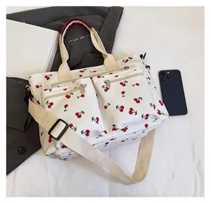 Close-up of cherry print canvas tote bag showing dual zipper pockets and size reference