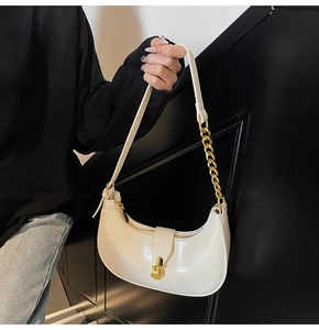Detail of creamy crescent bag showing golden buckle and metal chain leather strap