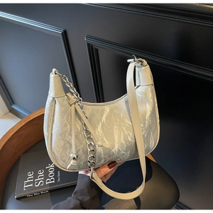 Détail du sac à bandoulière argenté marbré avec chaîne en métal sur une chaise noire