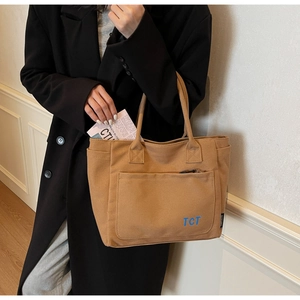 Detail shot of camel canvas tote bag with front zipper pocket and TCT logo embroidery