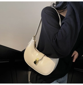 Detail of creamy white semi-circle hobo bag featuring glossy finish and gold metal buckle