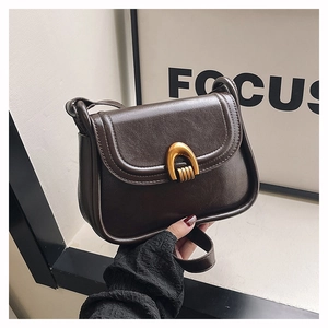 Close-up of a vintage brown leather saddle bag with a distinctive golden horseshoe buckle