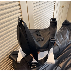 Detail of black nylon dumpling bag featuring wide adjustable strap and logo patch