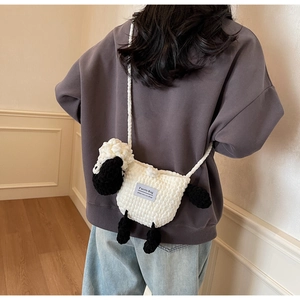 Detail of a handmade sheep-shaped knit crossbody bag showing texture and size on model