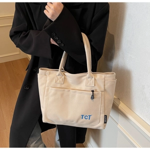 Close-up of durable canvas tote bag featuring an outer pocket and blue TCT embroidery