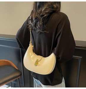 Detail of a minimalist off-white crescent hobo bag with glossy finish and gold clasp