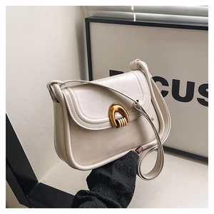 Close-up of cream retro saddle bag featuring a minimalist gold U-shaped metal buckle