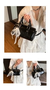 Close-up of black patent leather Boston bag featuring lace bow and pearl pendant details