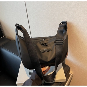 Detail of black nylon crescent bag featuring logo patch and wide shoulder strap