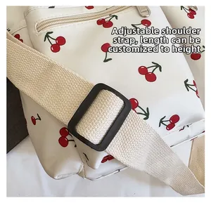 Detail of cherry print tote bag with adjustable beige strap and black plastic buckle