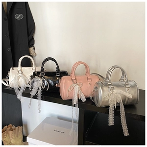 Detail of cylinder bags in four colors with lace bows, pearls, and leather straps