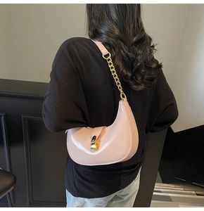 Pink crescent underarm bag featuring a metallic gold buckle and chain strap detail