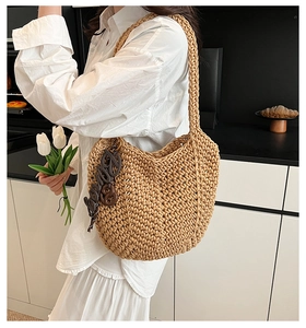 Détail du tissage en paille et du charm Love élégant sur le sac à bandoulière chic