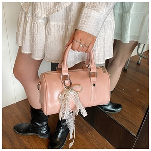 Detailed shot of pink glossy Boston bag featuring lace and pearl bow charms on it
