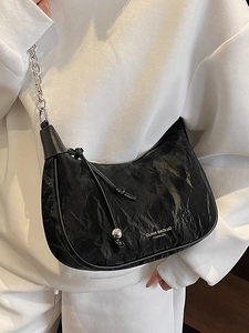 Sac bandoulière noir minimaliste avec texture froissée et chaîne porté par un modèle